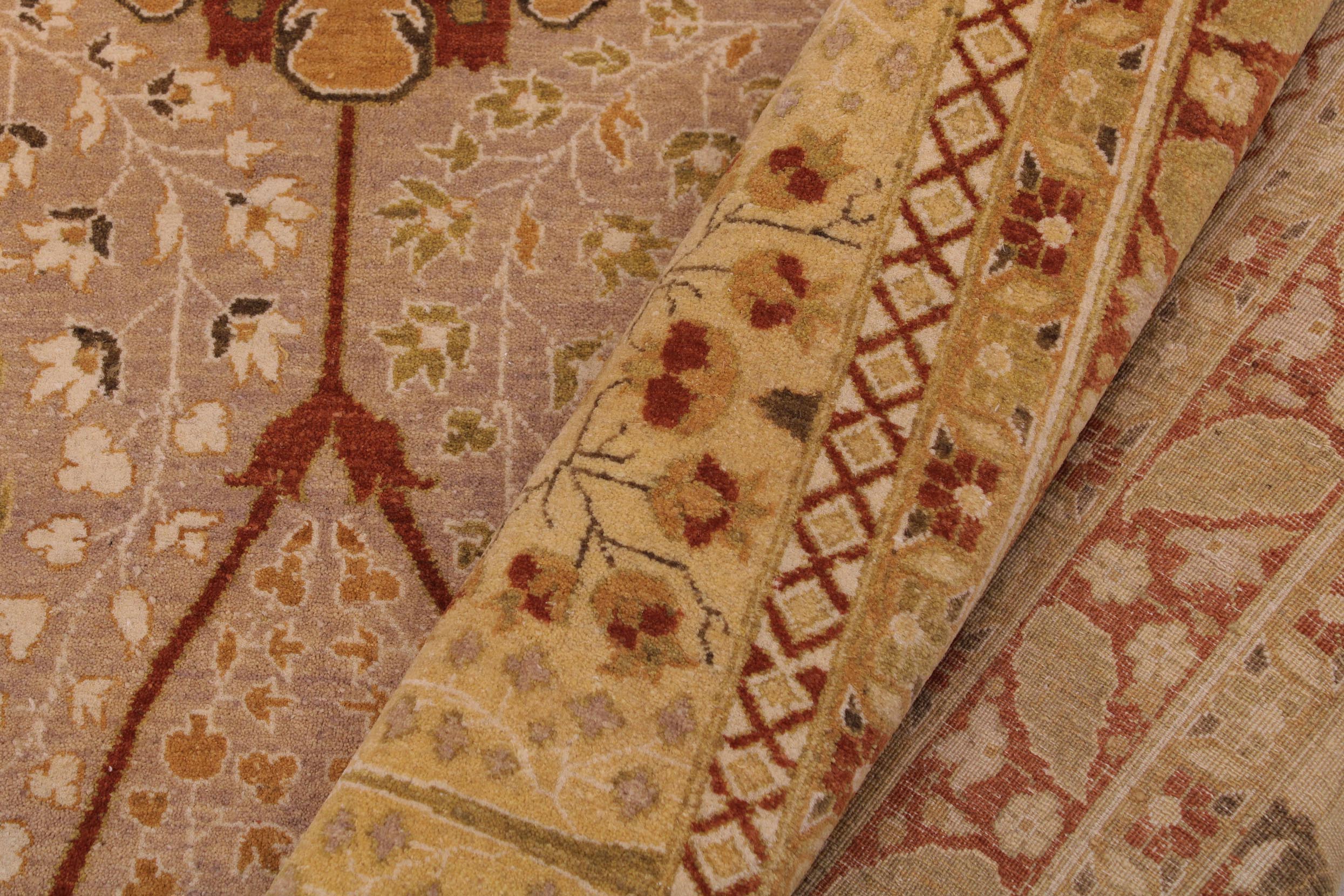 A close-up of a patterned area rug showing its detailed woven texture and traditional motifs in beige, rust red, and muted green.